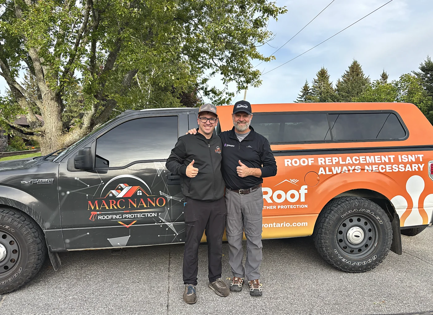 Steve and a dealer giving thumbs up in front of their branded trucks.