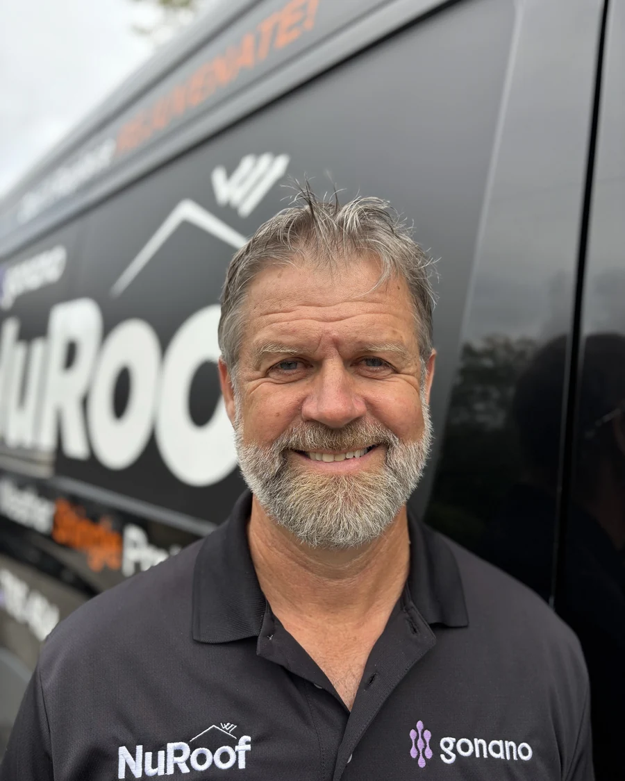 Steve Bevis in a gonano cap and polo shirt, standing in front of a branded vehicle.